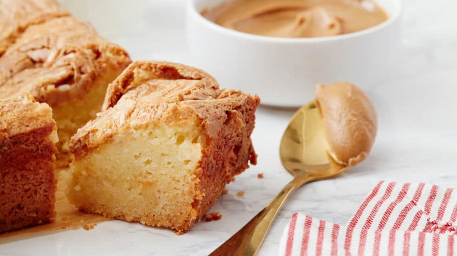 A slice of One-Bowl Cookie Butter Gooey Butter Bars next to a spoon of batter